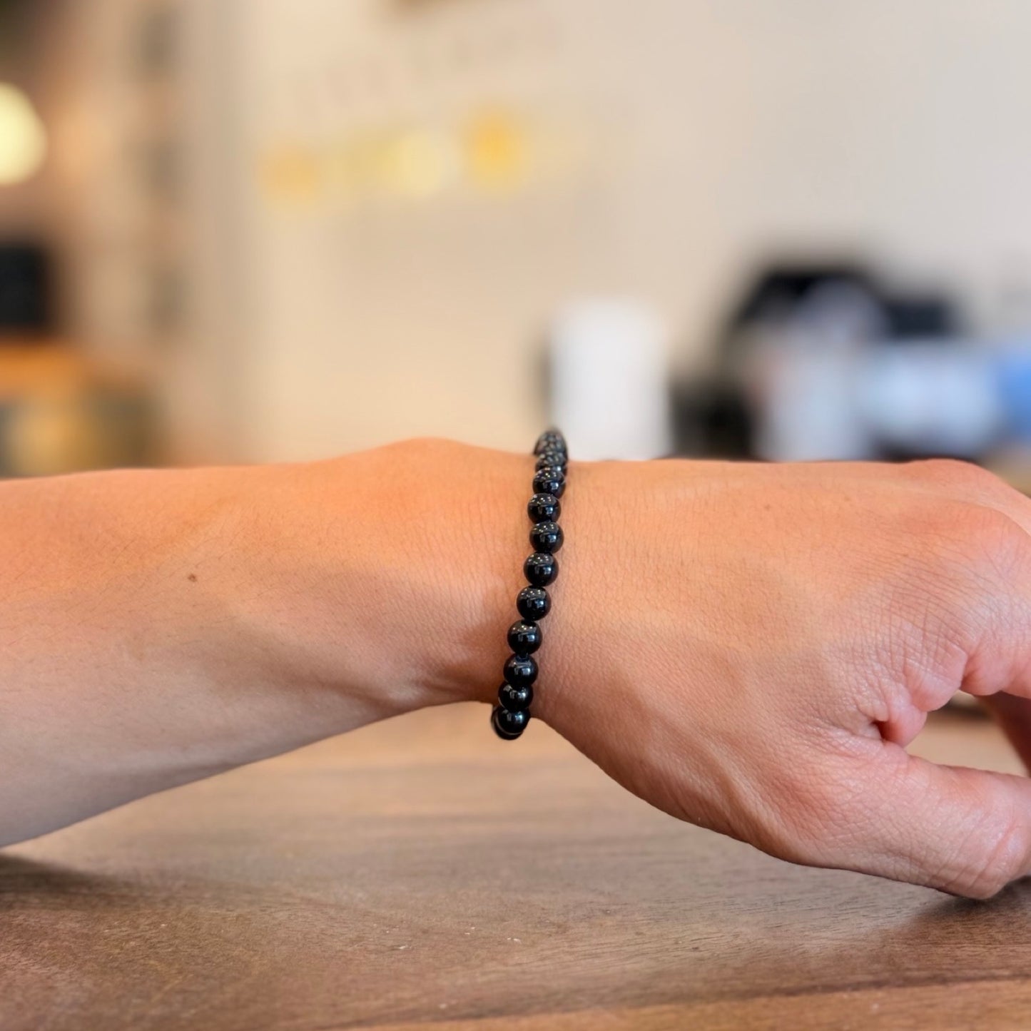 Men wearing a black Tourmaline bracelet on a wooden surface with a blurred background