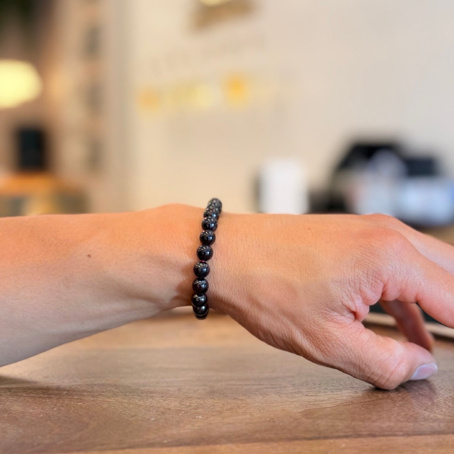 Men wearing a Garnet Bracelet bracelet on a wooden surface with a blurred background