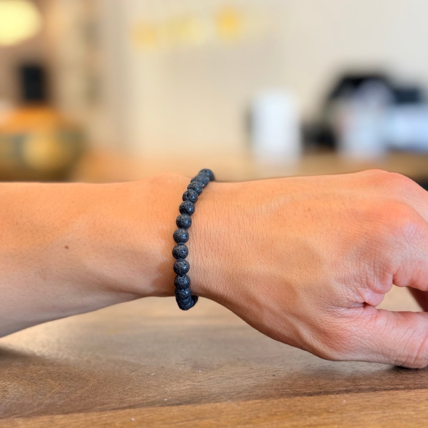 Men wearing Lave Stone bracelet on a blurred indoor background