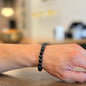 Person wearing a black Tourmaline bracelet on a blurred indoor background